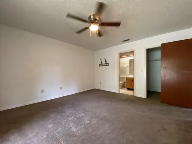 an empty room with closet and a ceiling fan