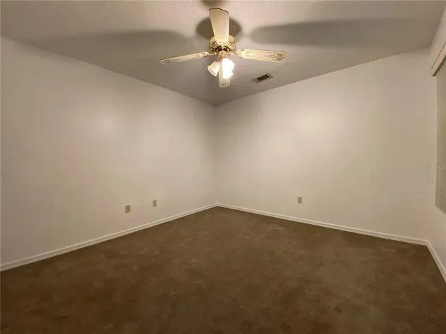 an empty room with a chandelier fan and ceiling fan