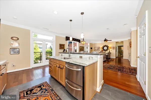a kitchen with stainless steel appliances granite countertop a refrigerator a sink dishwasher a dining table and chairs with wooden floor