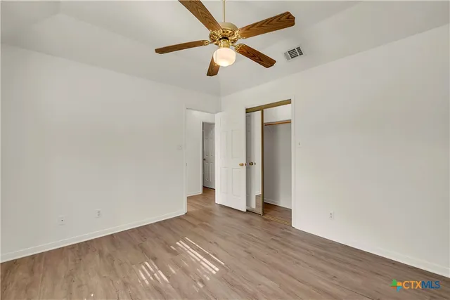 an empty room with wooden floor and ceiling fan