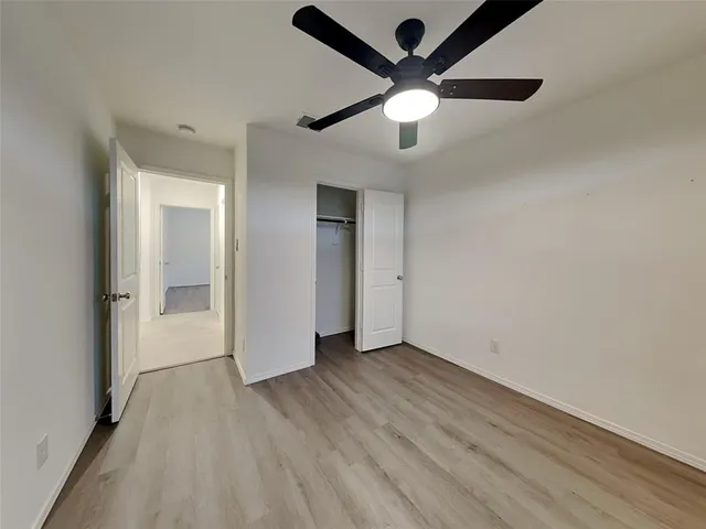 an empty room with wooden floor and a ceiling fan