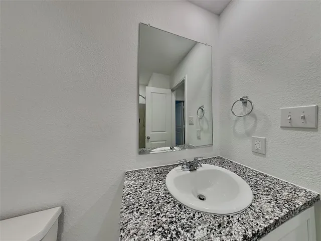 a bathroom with a granite countertop sink a mirror and a toilet