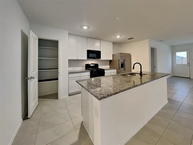 a kitchen with kitchen island granite countertop a stove and a sink