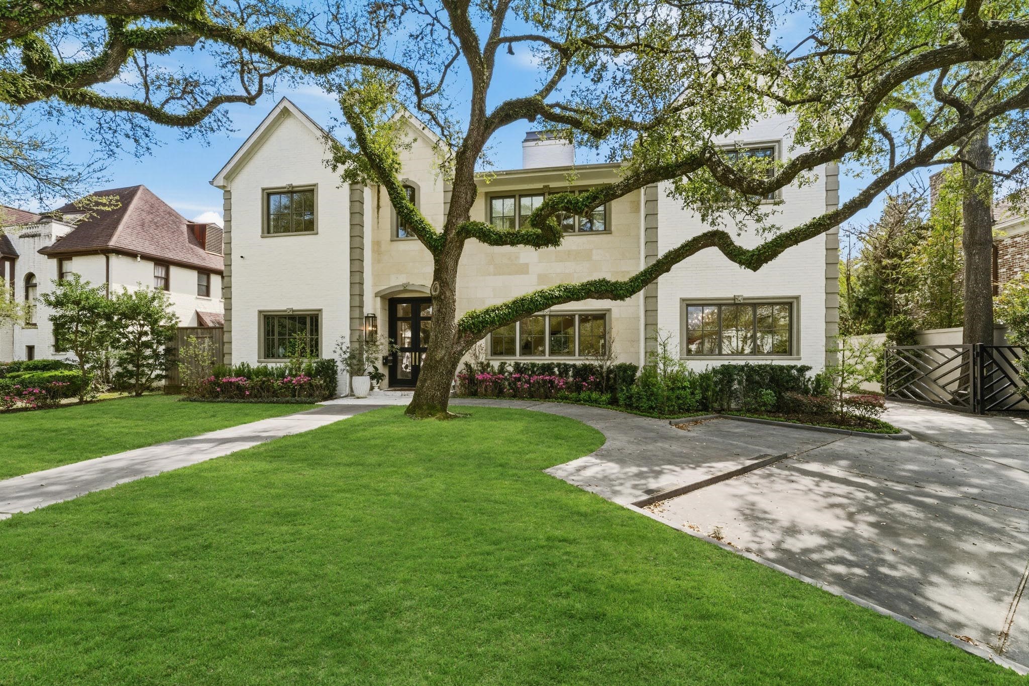 2211 Troon Road Houston, TX 77019 - Photo 2 of 44 a view of a white house next to a yard with big trees and plants