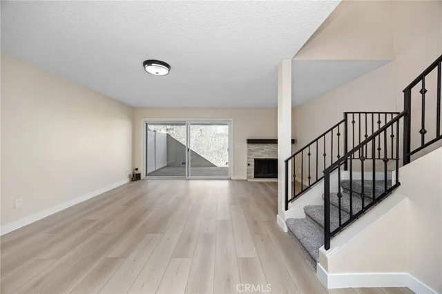 a view of an empty room with wooden floor entryway and a fireplace
