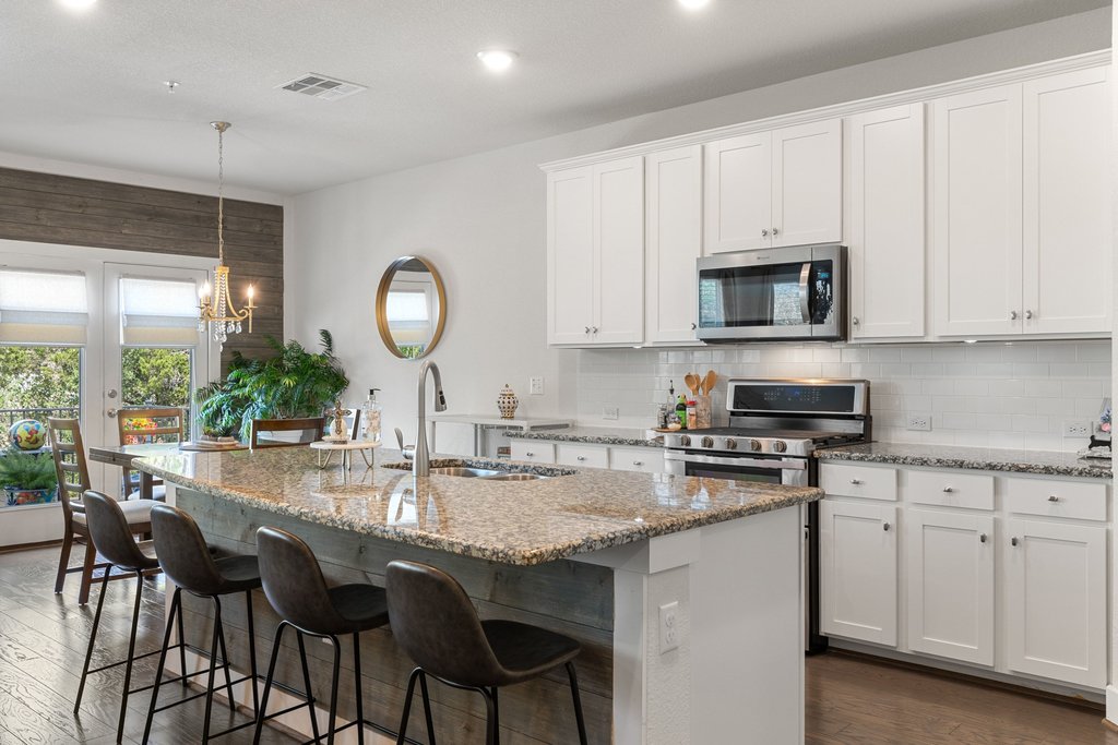 7409 Merrick Lane, Unit 40 Austin, TX 78745 - Photo 10 of 37 a kitchen with stainless steel appliances granite countertop a stove a sink dishwasher and white cabinets with wooden floor
