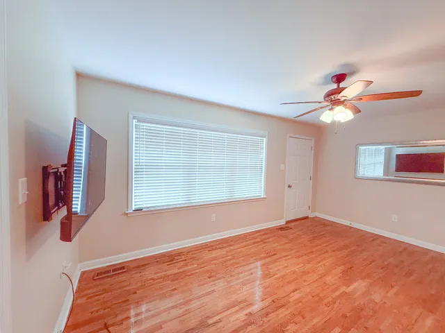 a view of an empty room with wooden floor and a window