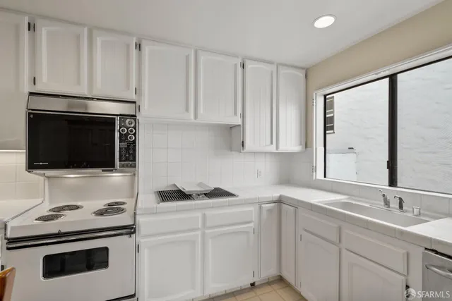 a kitchen with granite countertop white cabinets stainless steel appliances and sink
