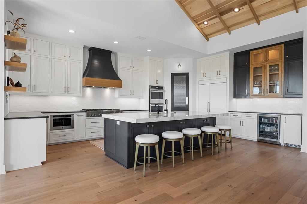 477 Wolf Creek Road Lorena, TX 76655 - Photo 12 of 40 a kitchen with stainless steel appliances granite countertop a stove top oven a sink a dining table and chairs with wooden floor