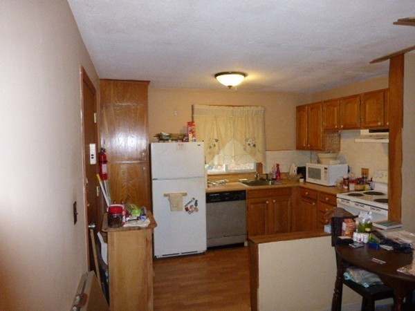 11 Jacqueline Road, Unit D Waltham, MA 02452 - Photo 4 of 13 a kitchen with a refrigerator a stove a sink dishwasher and wooden cabinets