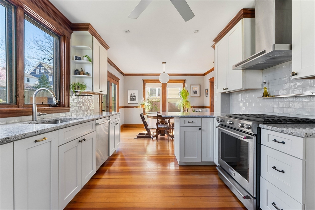 136 Beech Street Boston, MA 02131 - Photo 14 of 40 a kitchen with stainless steel appliances granite countertop hardwood floor sink stove dining table and chairs