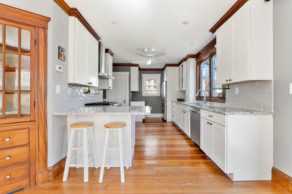 136 Beech Street Boston, MA 02131 - Photo 15 of 40 a kitchen with stainless steel appliances granite countertop a refrigerator a sink dishwasher a stove and white cabinets with wooden floor