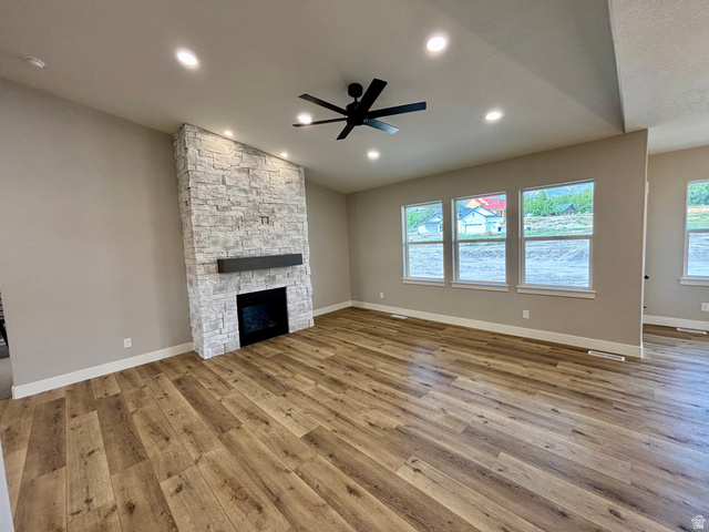 1184 West 3250 North Ogden, UT 84414 - Photo 15 of 69 Spacious living area featuring a floor-to-ceiling stacked stone fireplace with a dark wood-finish mantel, lap style wood flooring, recessed lighting and a large ceiling fan