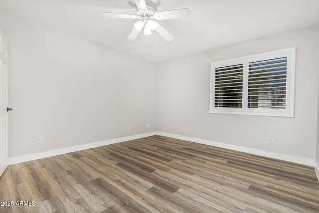 a view of empty room with wooden floor and fan