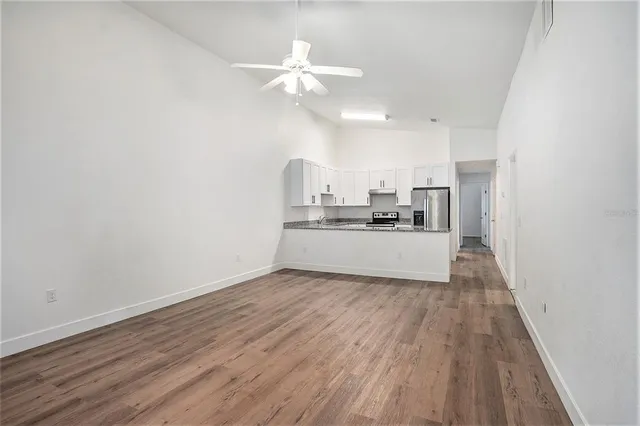 a view of a kitchen with a sink a refrigerator and wooden floor