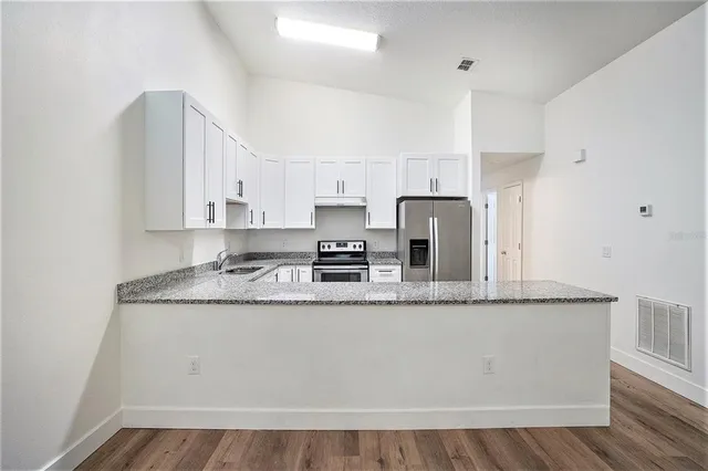 a kitchen with stainless steel appliances granite countertop a sink a refrigerator a microwave and cabinets