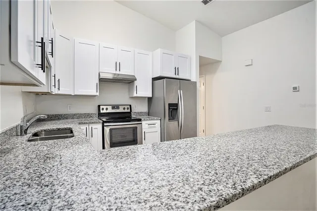 a kitchen with granite countertop a sink stove and refrigerator