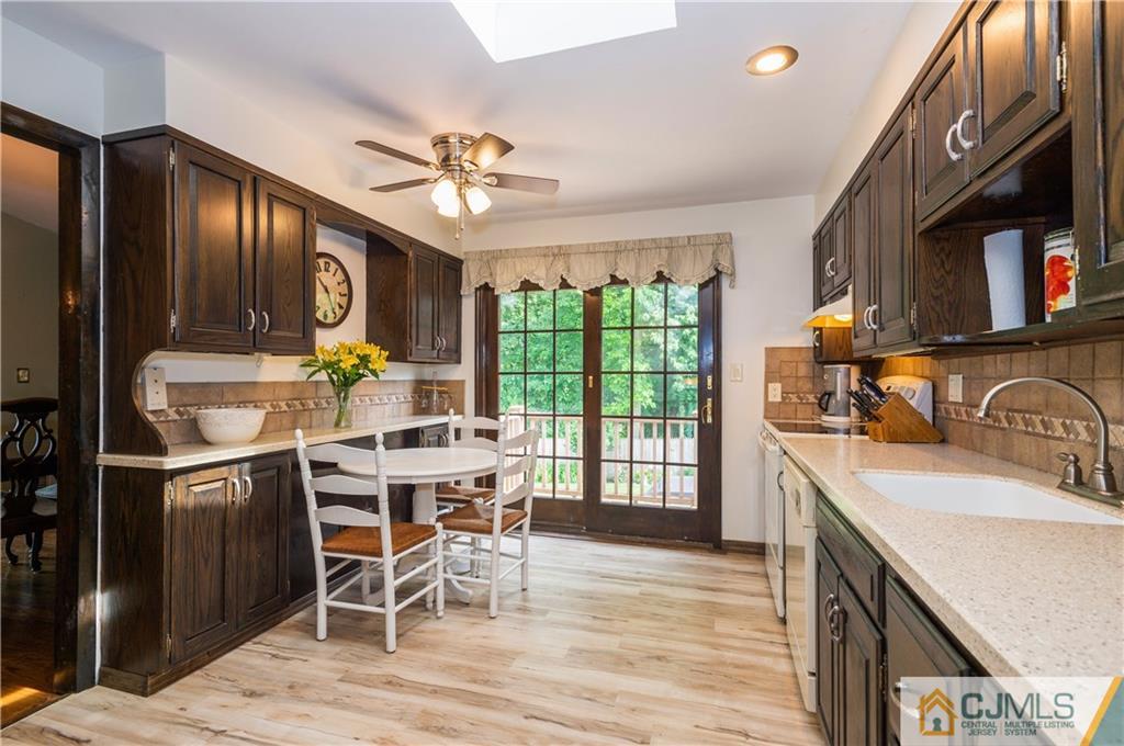 70 Wilk Road Edison, NJ 08837 - Photo 12 of 24 a kitchen with stainless steel appliances granite countertop a stove top oven a sink dishwasher a dining table and chairs with wooden floor