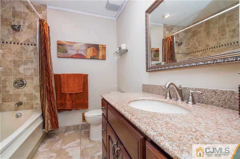 70 Wilk Road Edison, NJ 08837 - Photo 17 of 24 a bathroom with a granite countertop sink a toilet a mirror a bathtub and shower