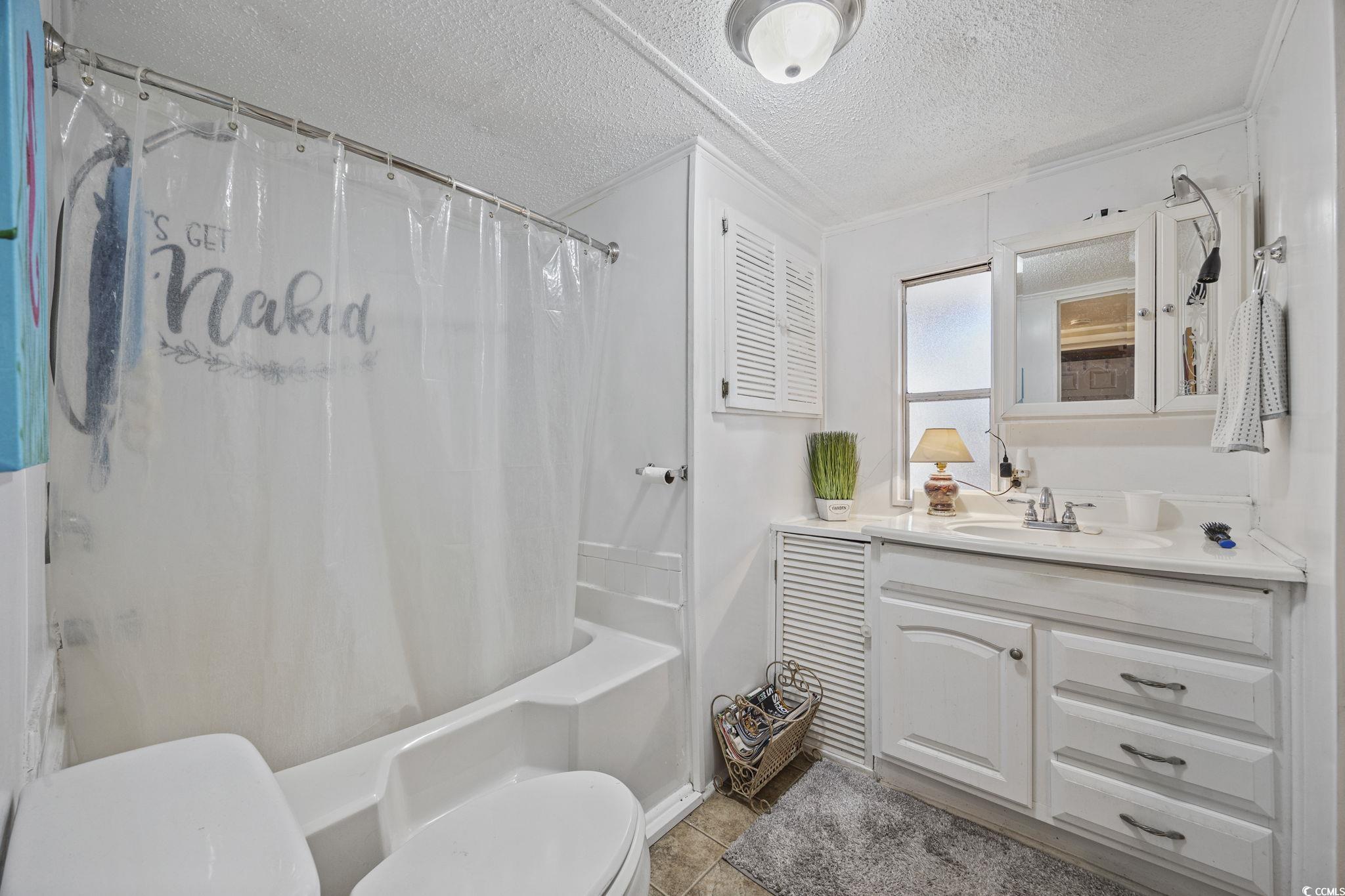 80 Princess Drive North Myrtle Beach, SC 29582 - Photo 12 of 27 Full bathroom with vanity, a textured ceiling, shower / tub combo with curtain, and light tile patterned flooring