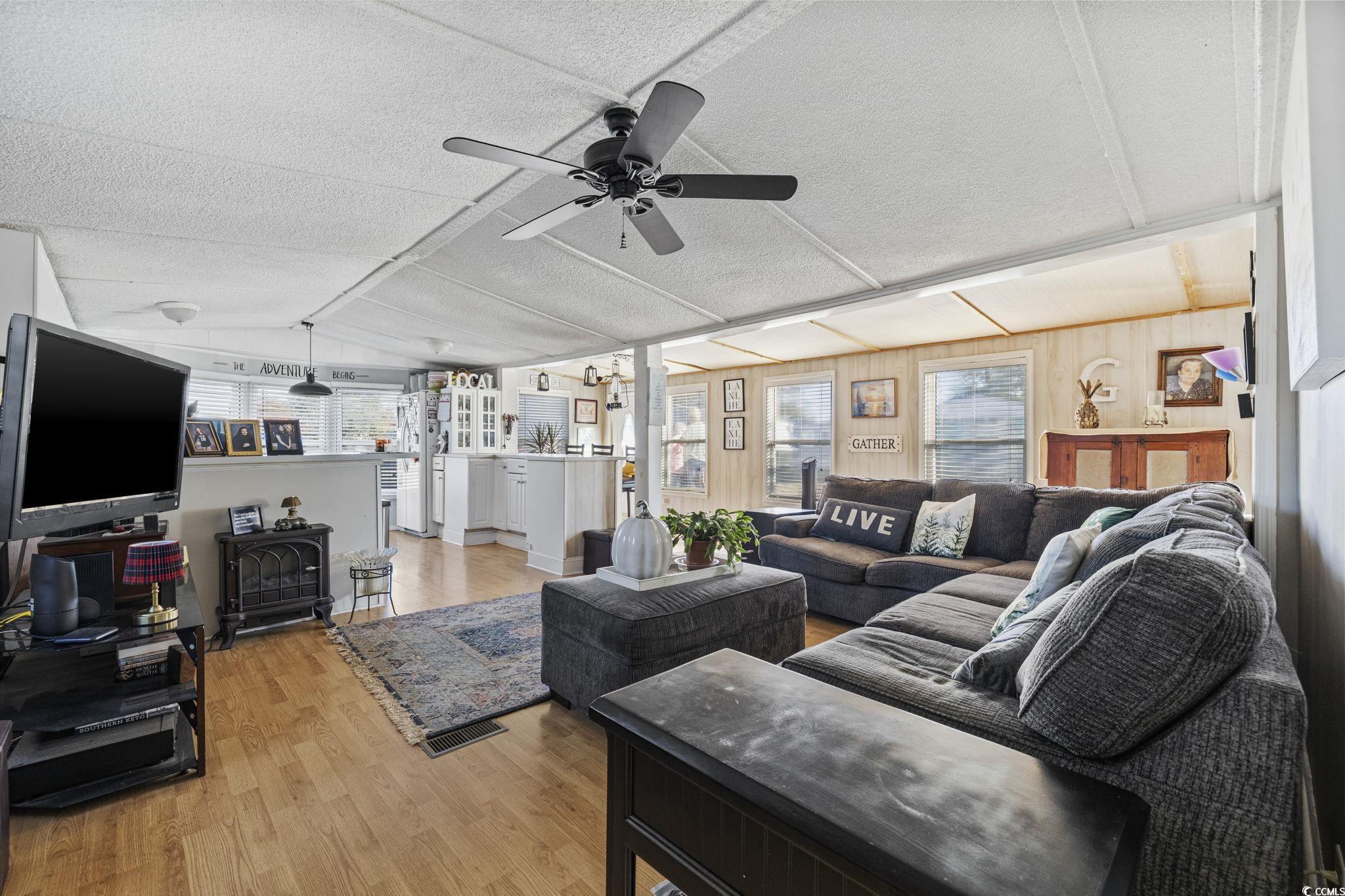 80 Princess Drive North Myrtle Beach, SC 29582 - Photo 17 of 27 Living room featuring plenty of natural light, light wood-style flooring, ceiling fan, lofted ceiling, and a textured ceiling