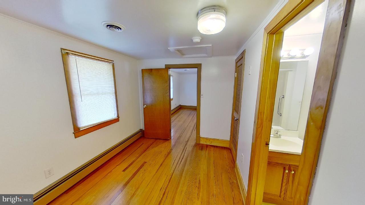 42464 Fairgrounds Road Leonardtown, MD 20650 - Photo 21 of 33 a hallway with wooden floor and a bathroom