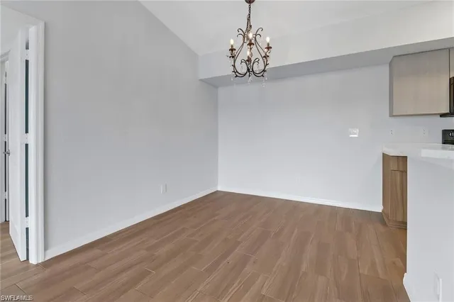 a view of a hallway with wooden floor and a chandelier