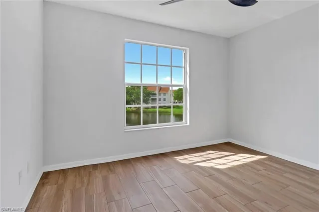 a view of empty room with wooden floor and fan