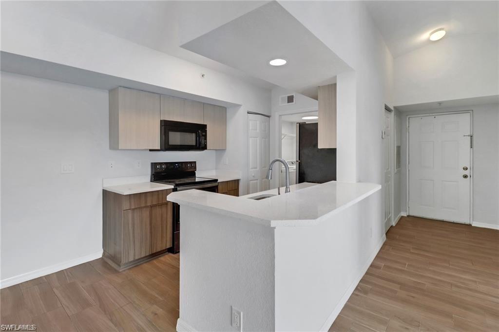 4720 St Croix Lane, Unit 135 Naples, FL 34109 - Photo 18 of 24 a living room with stainless steel appliances kitchen island a sink a microwave a refrigerator and a stove top oven