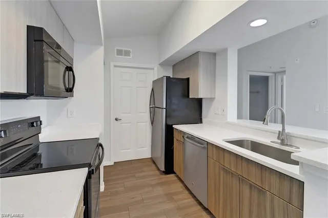a kitchen that has a sink a refrigerator and a microwave