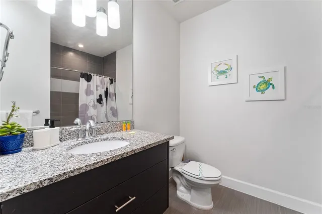 a bathroom with a granite countertop bathtub sink vanity mirror and toilet