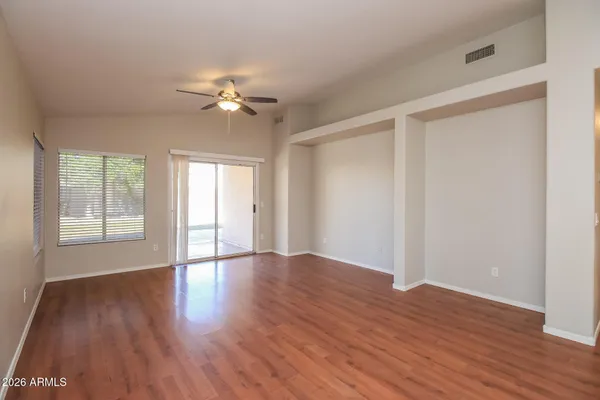 a view of an empty room with wooden floor and a window
