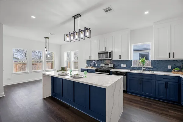 a kitchen with a sink a center island a wooden floor and cabinets