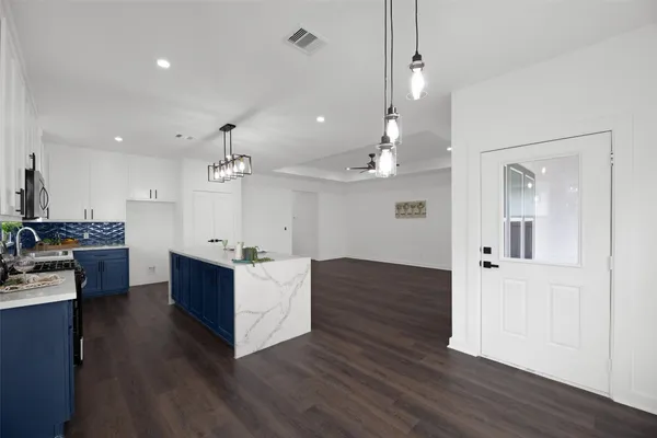 a kitchen with kitchen island white cabinets and refrigerator
