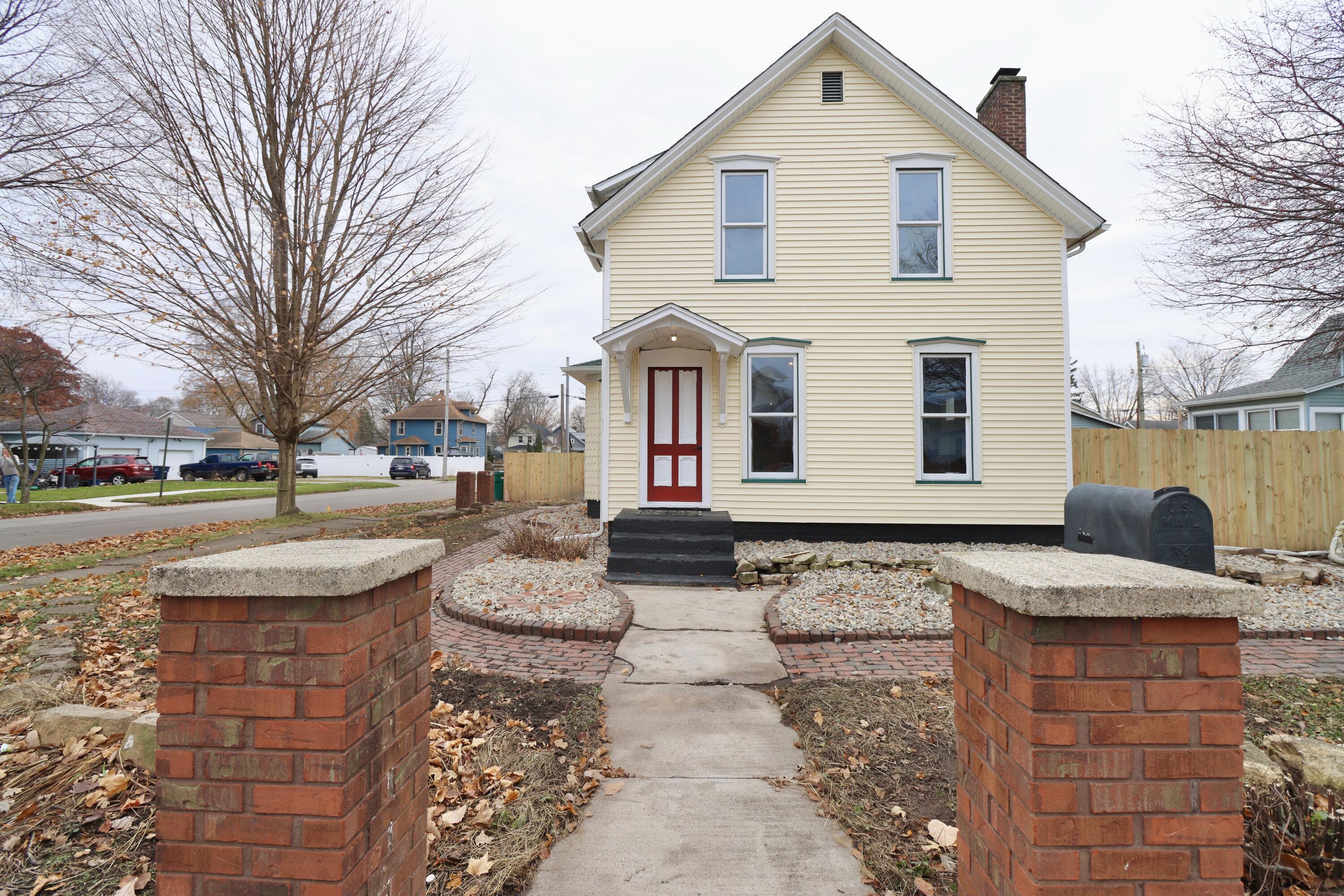 a front view of a house with garden and trees