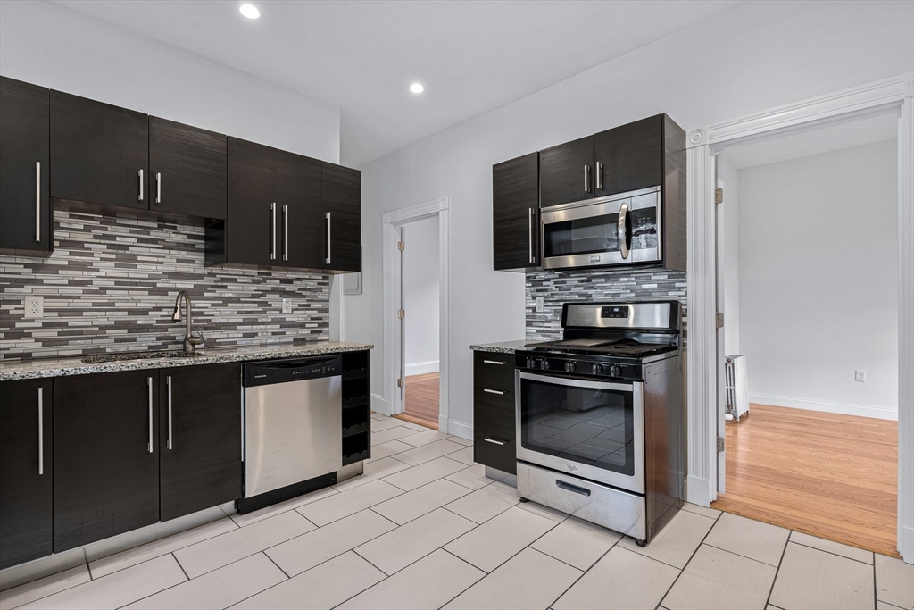 a kitchen with stainless steel appliances kitchen island granite countertop a stove sink and microwave