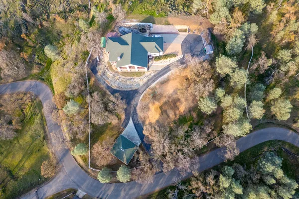 an aerial view of a house with a yard and large trees