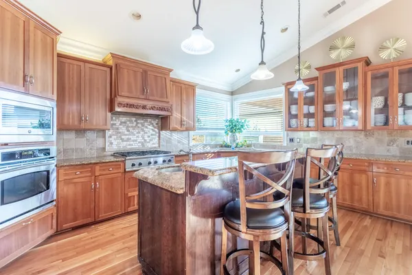 a kitchen with stainless steel appliances granite countertop a stove top oven a dining table and chairs with wooden floor