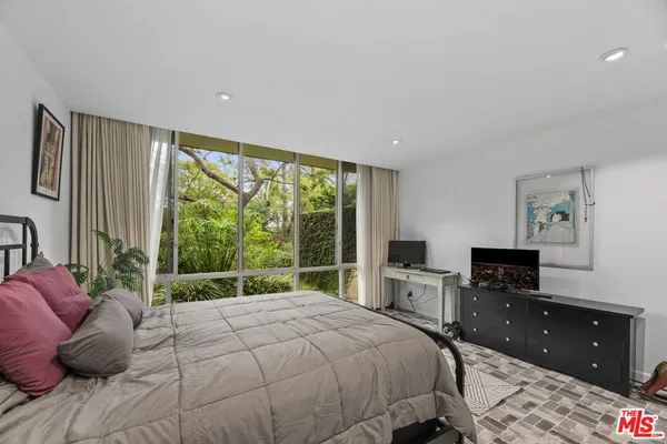 a bedroom with a bed and large windows