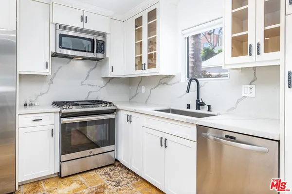 a kitchen with stainless steel appliances a stove microwave and sink