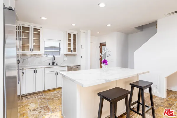 a kitchen with granite countertop white cabinets and chairs