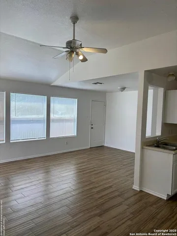 a view of empty room with wooden floor and fan