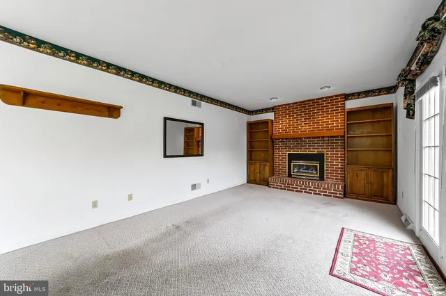 a view of an empty room with a fireplace and a window