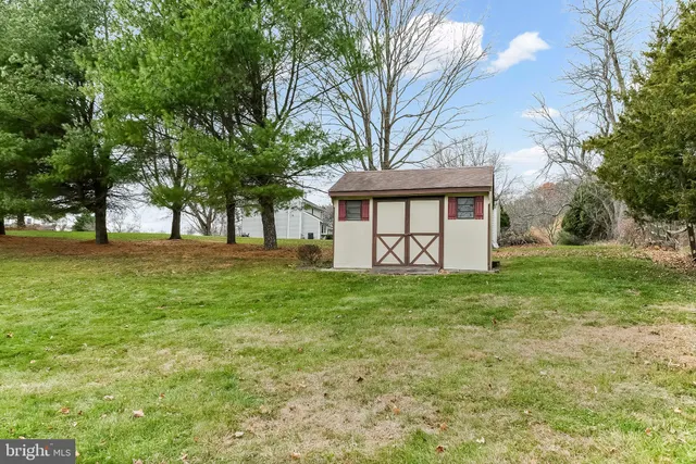 a view of a white house with a big yard and large trees