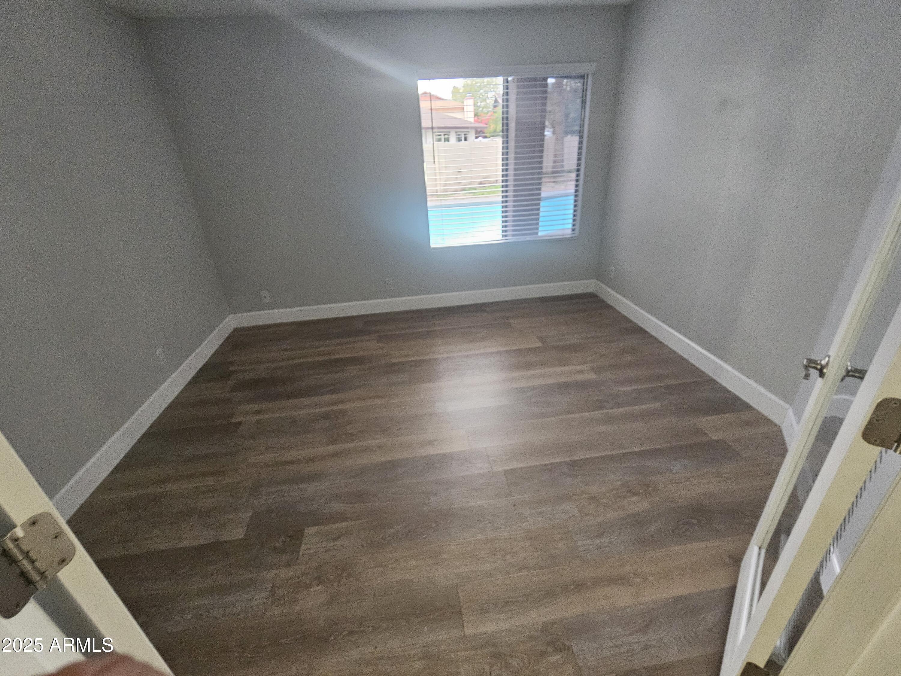 10032 West Sells Drive Phoenix, AZ 85037 - Photo 9 of 19 an empty room with wooden floor and windows