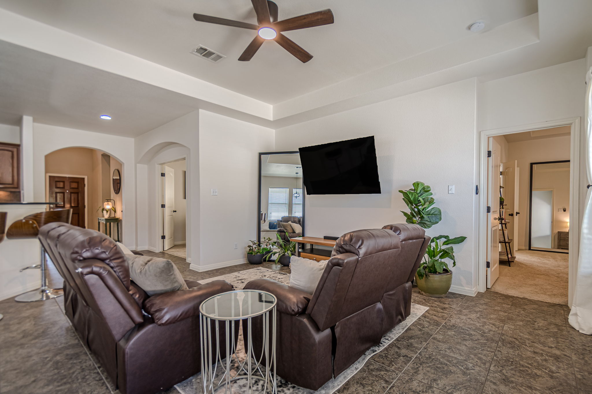 1031 Powell Kyle, TX 78640 - Photo 14 of 40 Living area featuring ceiling fan, arched walkways, and a tray ceiling