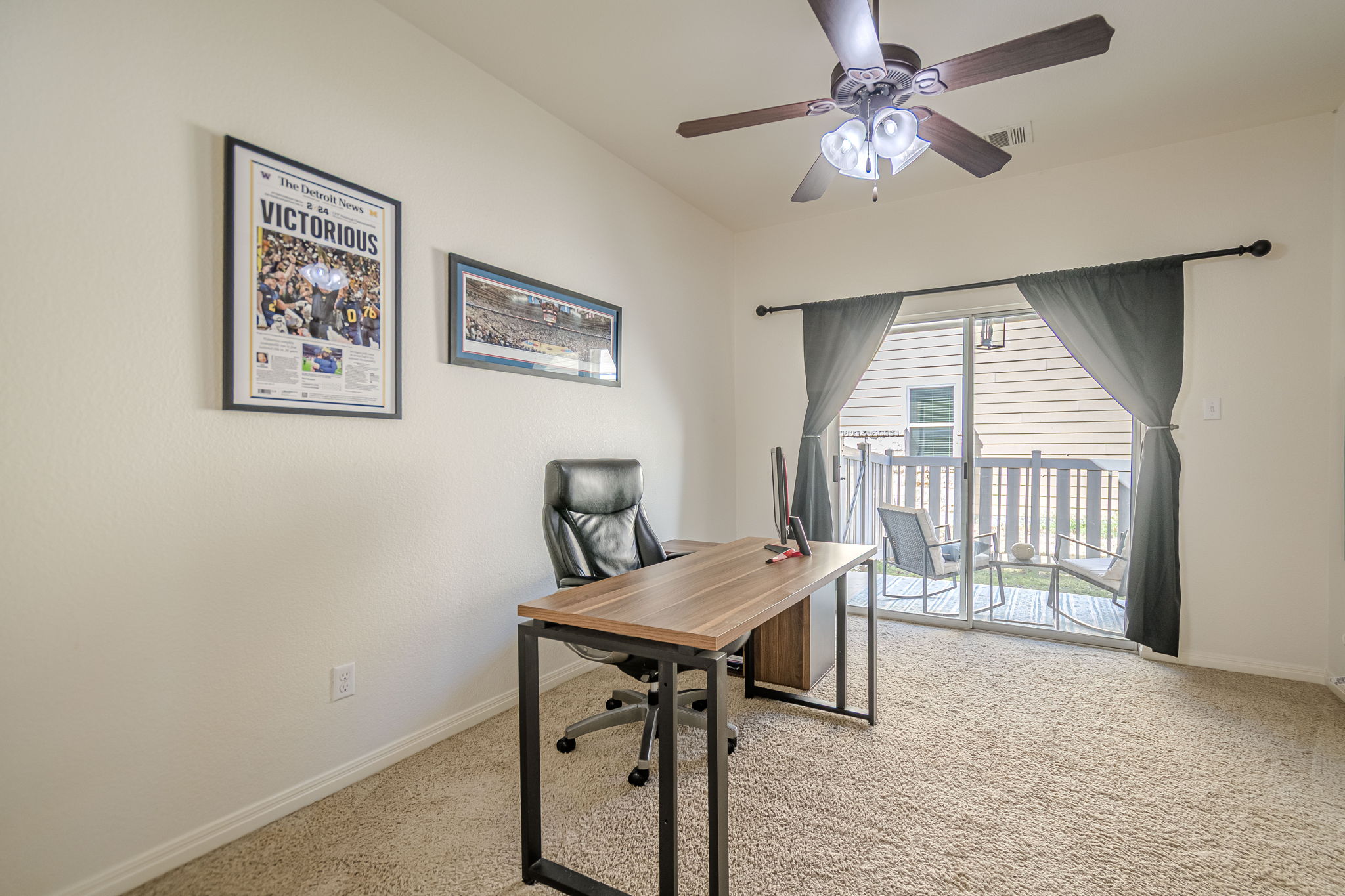 1031 Powell Kyle, TX 78640 - Photo 21 of 40 Bedroom 4 being used as an office space with light carpet and a ceiling fan and looking out at private covered patio