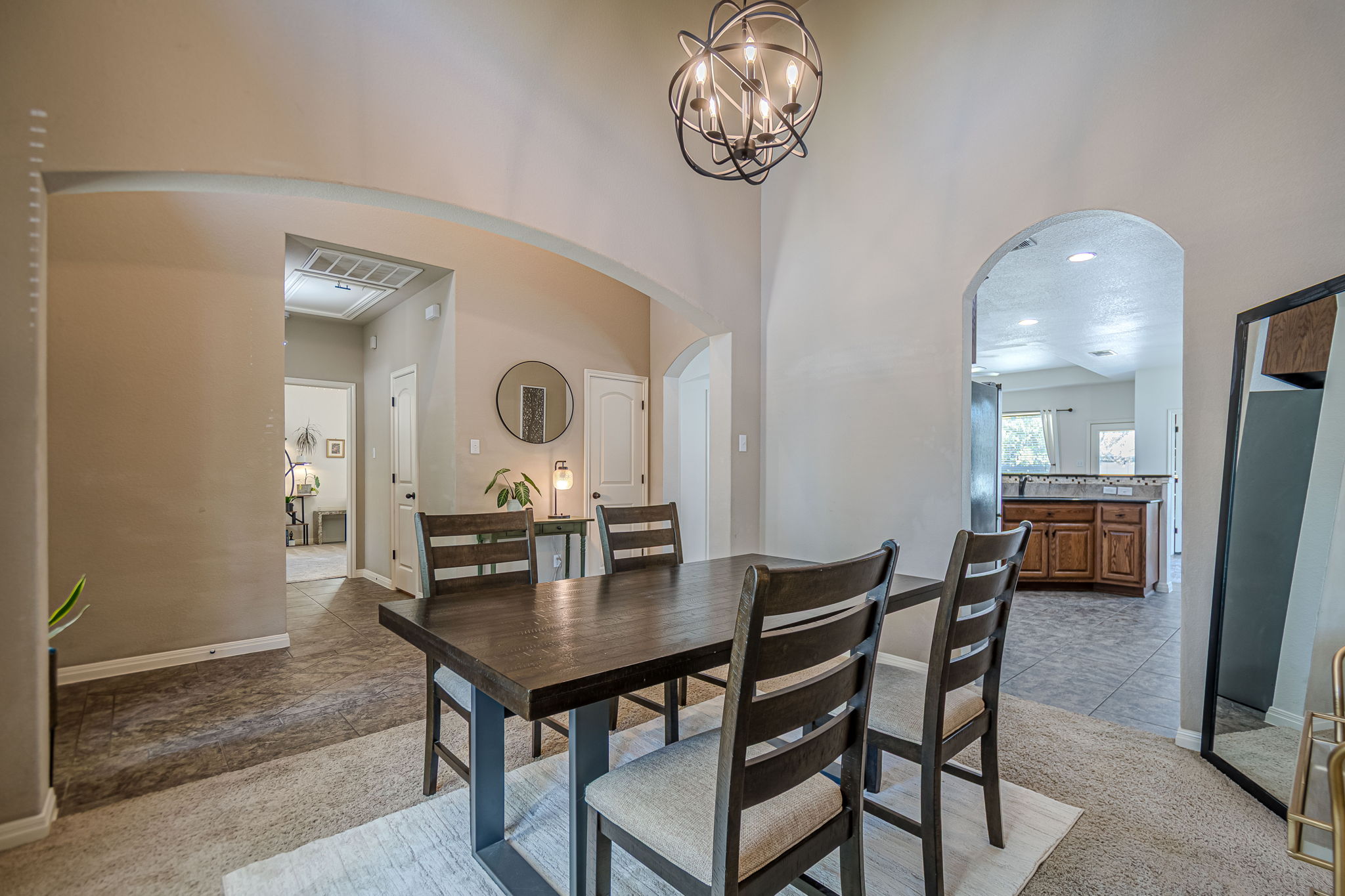 1031 Powell Kyle, TX 78640 - Photo 6 of 40 Dining area with light carpet, arched walkways, suspended lighting, light tile patterned flooring, and a high ceiling