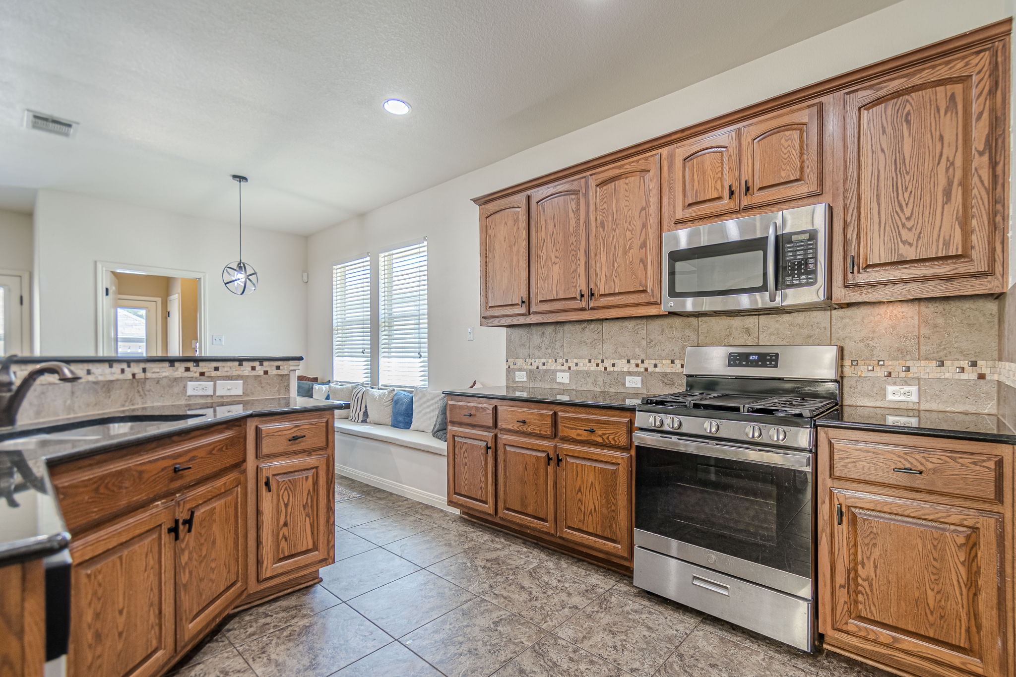 1031 Powell Kyle, TX 78640 - Photo 8 of 40 Kitchen with stainless steel appliances, wood cabinets, dark granite countertops, and decorative backsplash