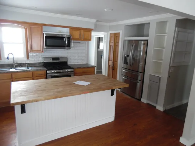 a kitchen with stainless steel appliances wooden floor and a refrigerator